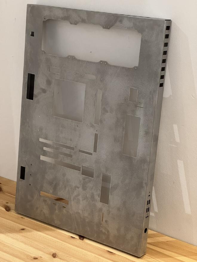 Photograph of the &ldquo;case&rdquo; as received from the shop: unfinished metal with many square holes, even on the side